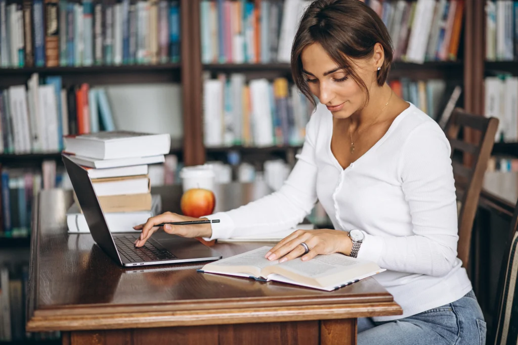 Woman studying with laptop and books in library